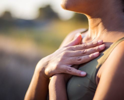 A person is breathing in, with their hands on their chest.